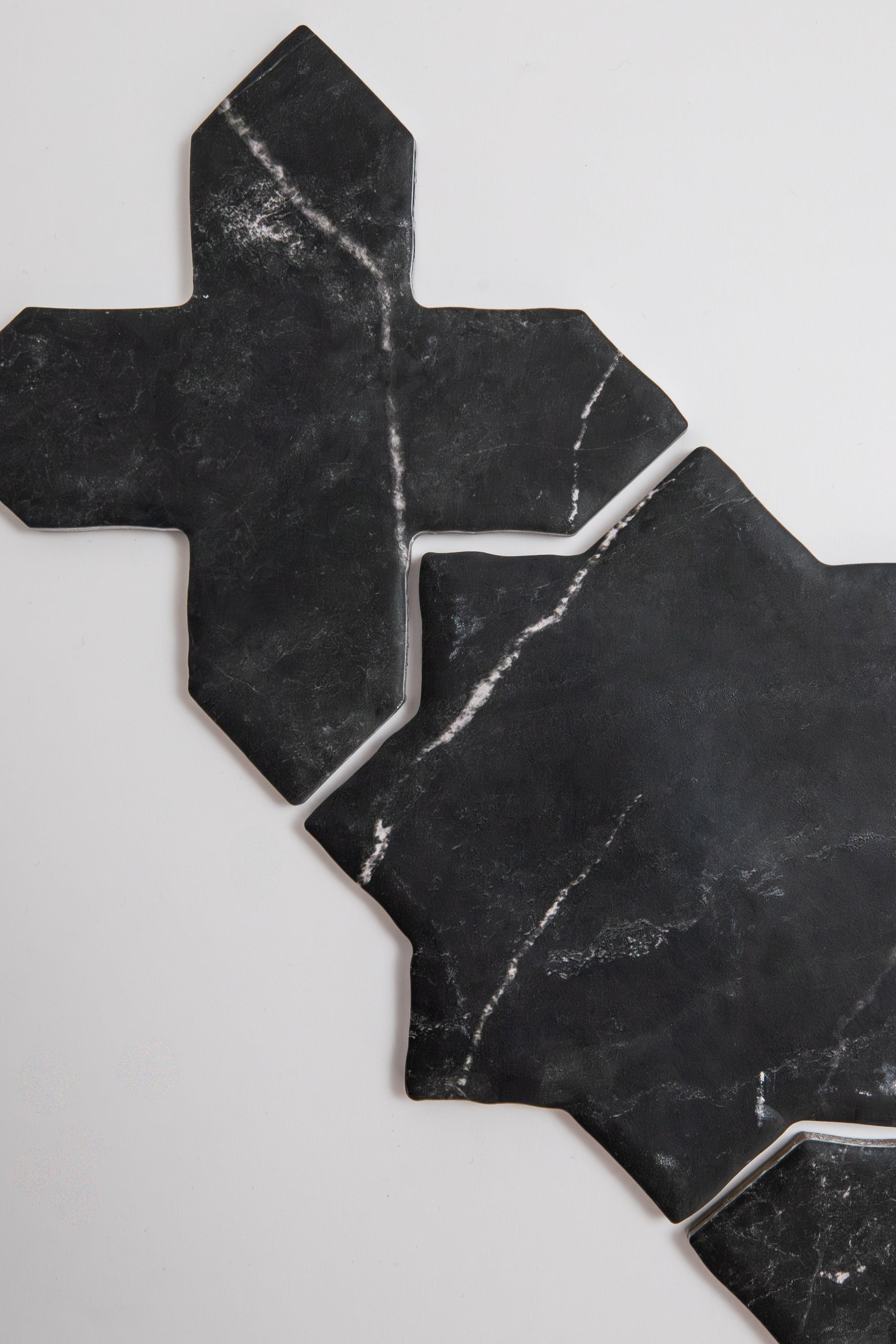 Two Black Marble, Extra Sample tiles by Tosca feature geometric cross shapes on a white background.