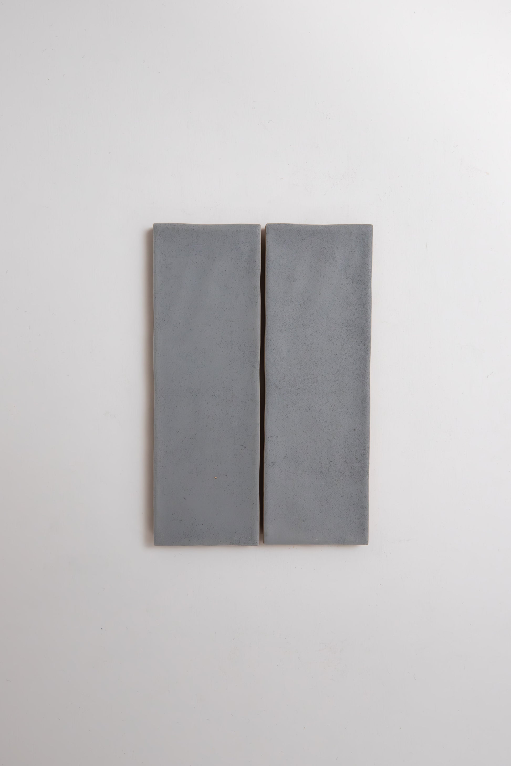 Two rectangular Bourton Dark Blue tiles by Cottage Ivy are mounted side by side on a white wall with a narrow gap.