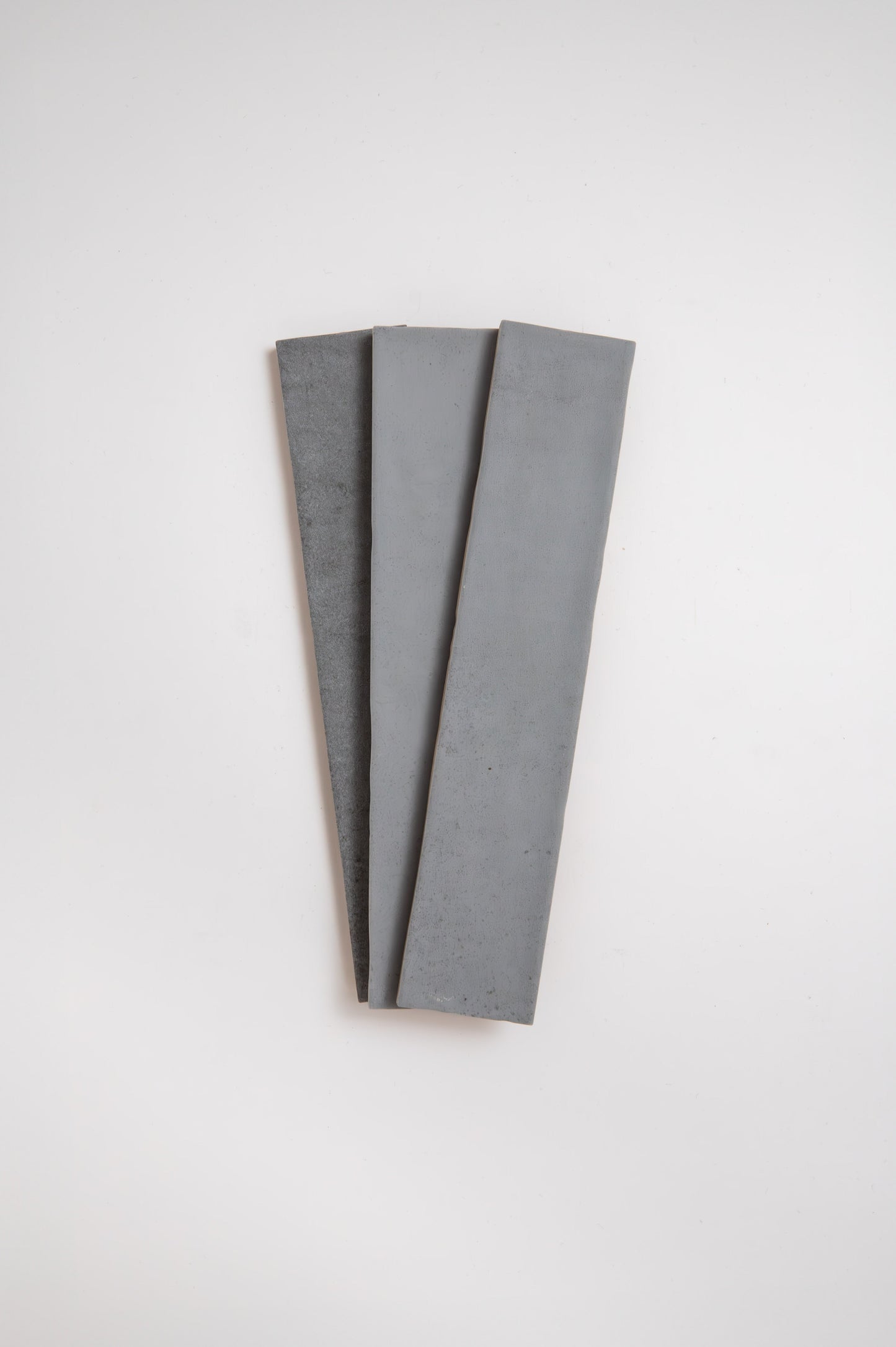 Three Bourton Dark Blue tiles by Cottage Ivy, arranged in a fanned-out pattern on a white background.