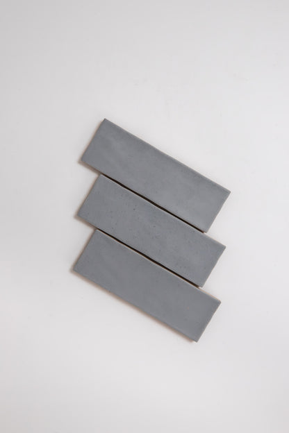 Three Bourton Dark Blue tiles by Cottage Ivy are arranged diagonally in a staggered stack on a white background.