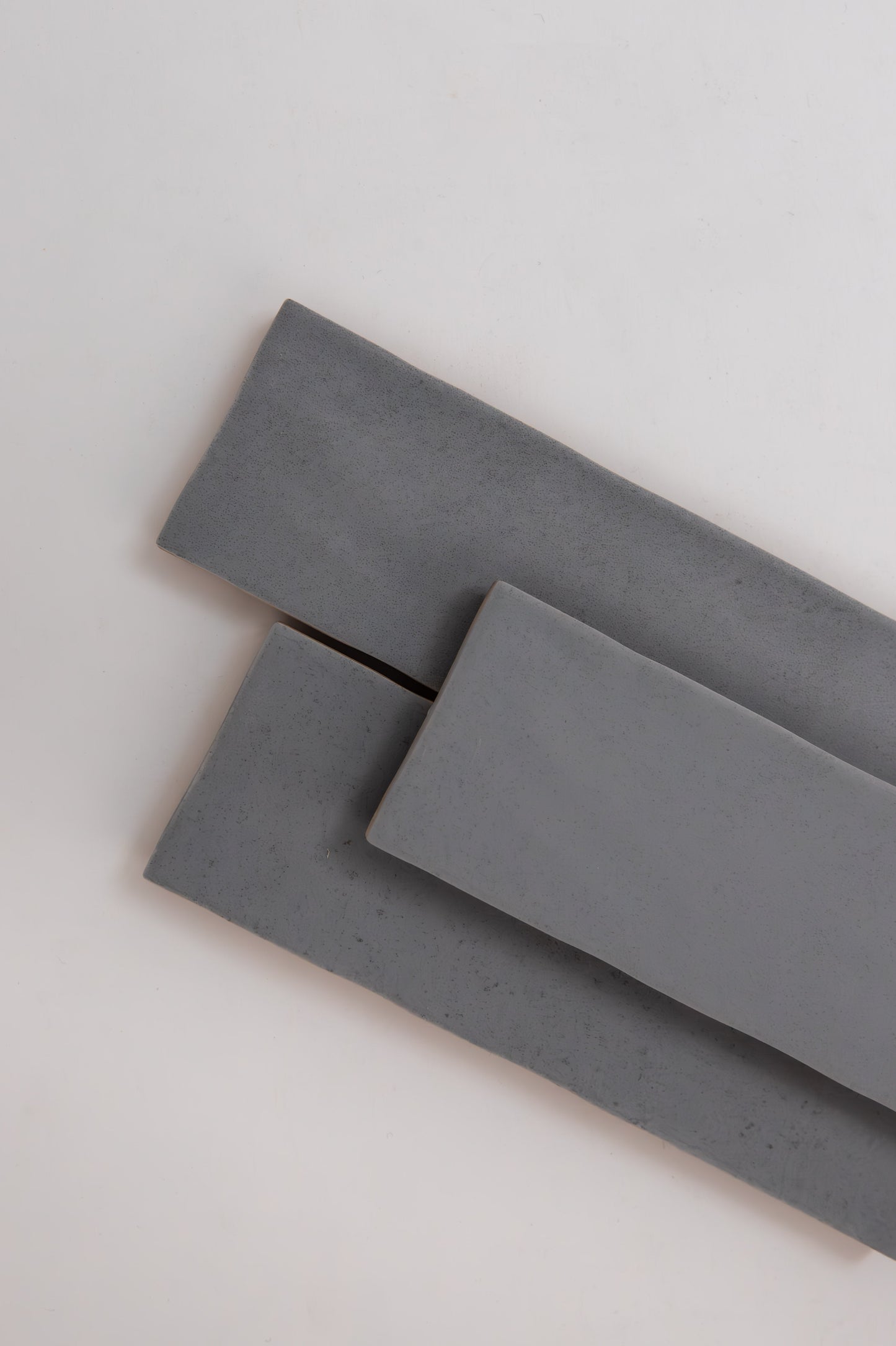 Three overlapping Bourton Dark Blue tiles by Cottage Ivy on a plain, light-colored background.