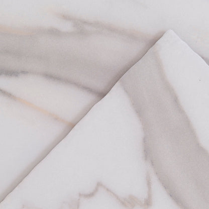 Close-up of two overlapping Tosca Calacatta Gold marble surfaces with light gray and beige veins.