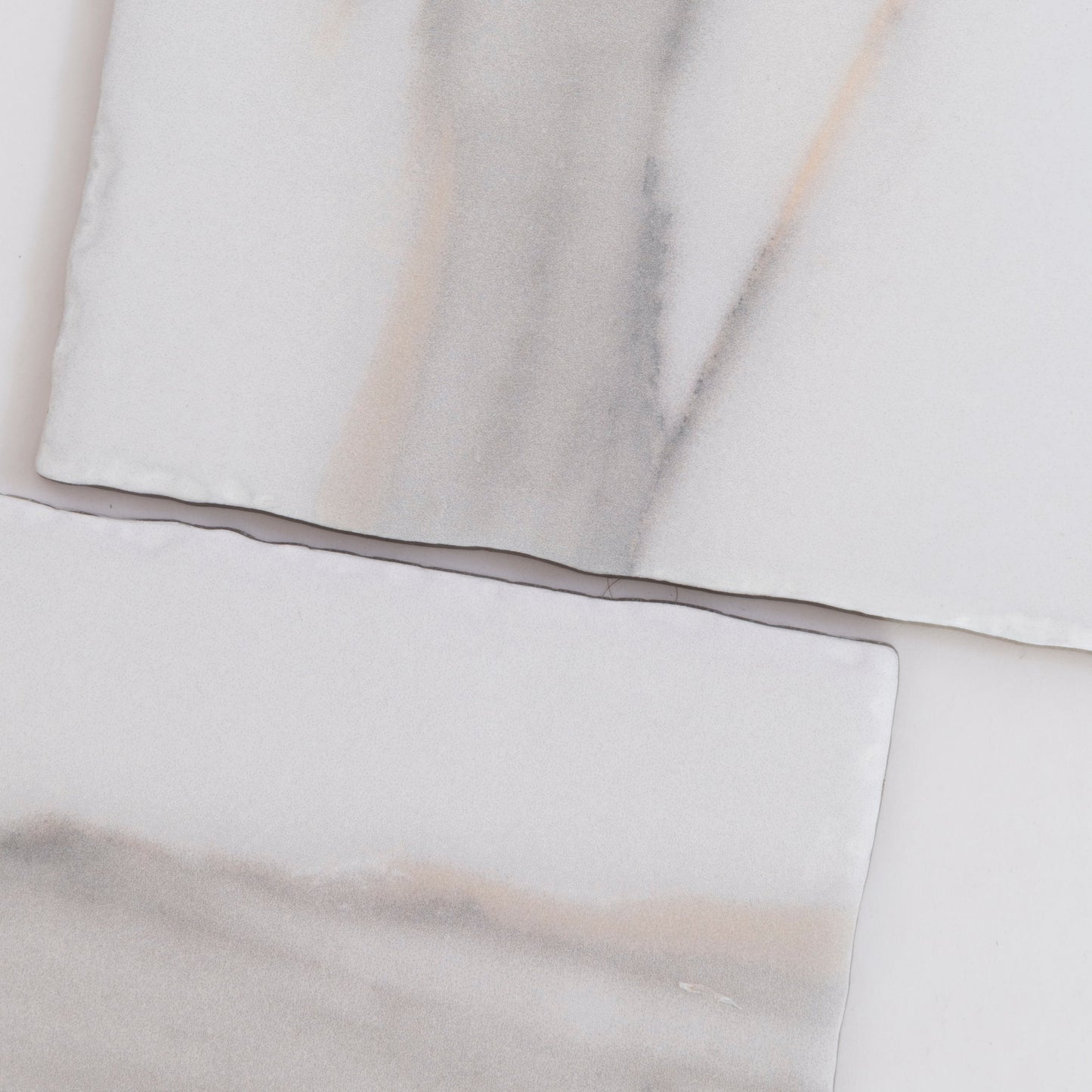 Two rectangular Tosca Calacatta Gold marble tiles with subtle gray and beige veining on a white background.