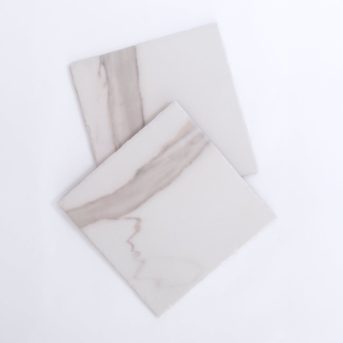 Two Tosca Calacatta Gold square tiles with light gray veining overlap on a plain white background.