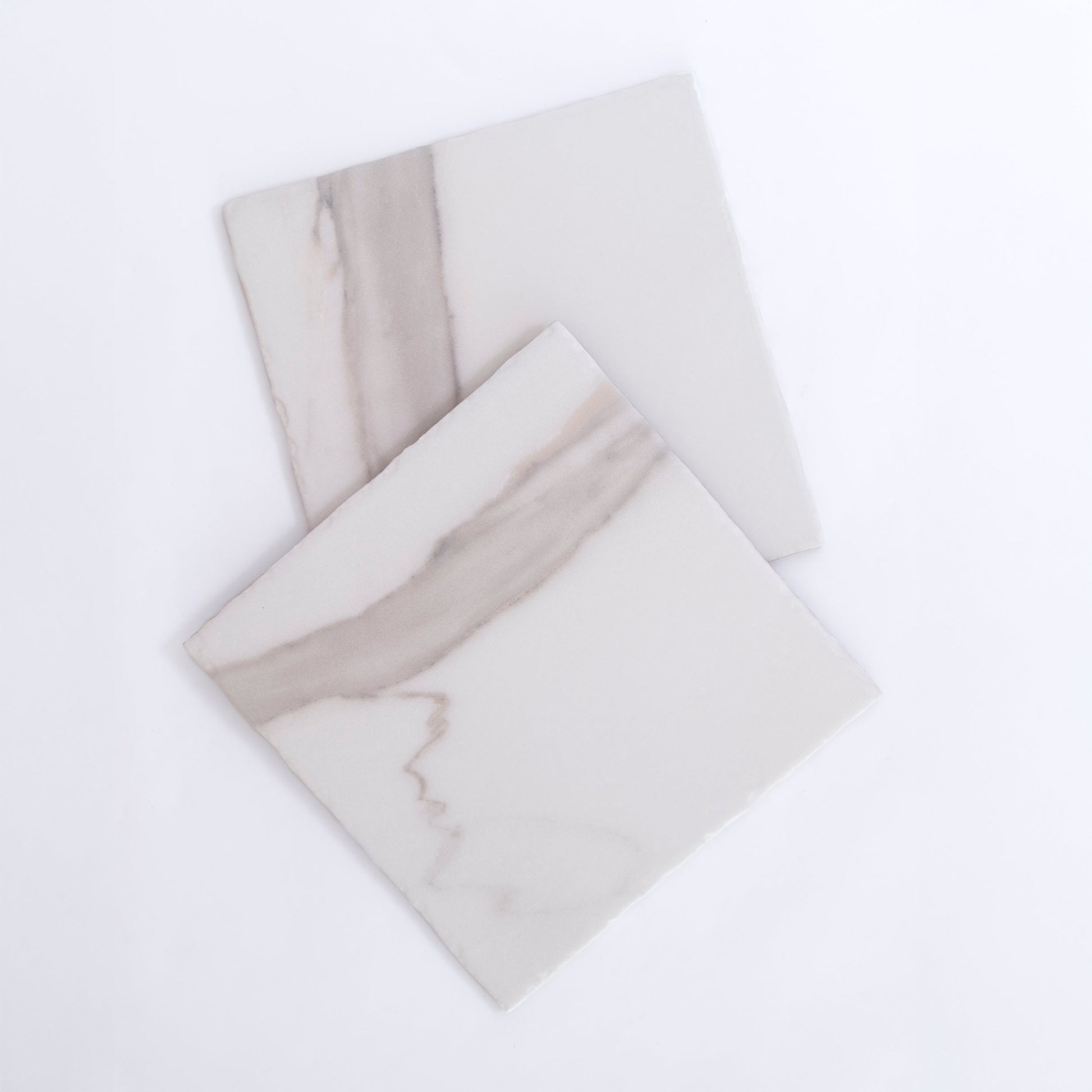 Two Tosca Calacatta Gold square tiles with light gray veining overlap on a plain white background.