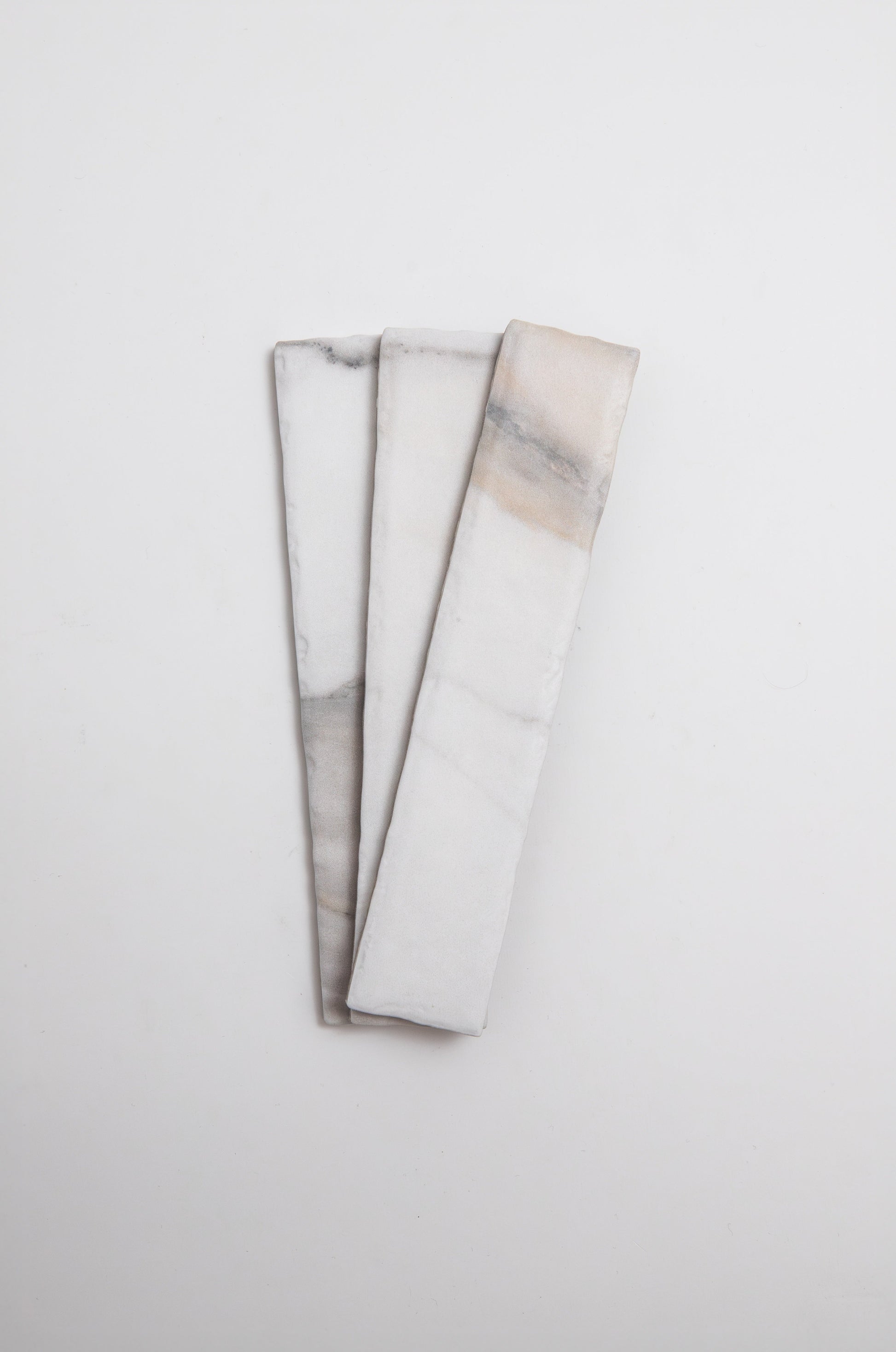 Three Tosca Calacatta Gold marble tiles with gray and beige streaks, side by side on a white background.