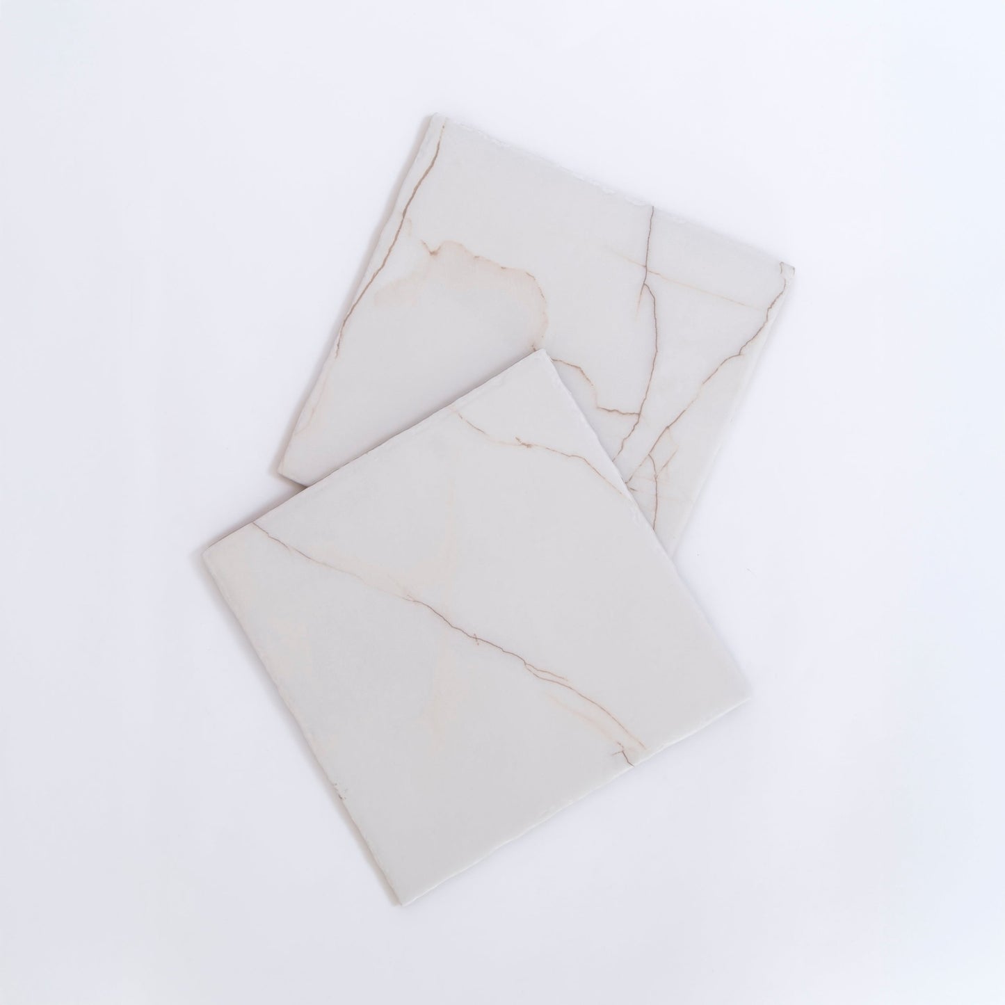 Two Calacatta Soft marble tile samples by Tosca, white with subtle beige veins, overlap on a white background.