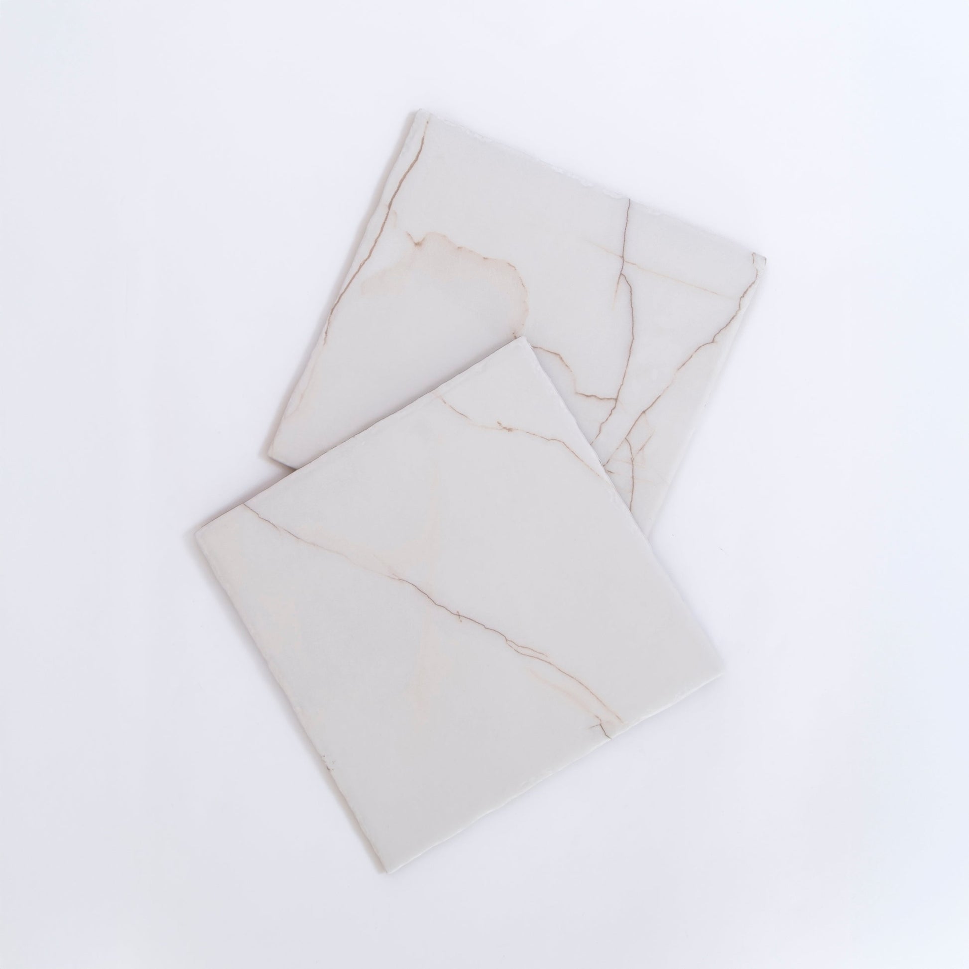 Two Calacatta Soft marble tile samples by Tosca, white with subtle beige veins, overlap on a white background.
