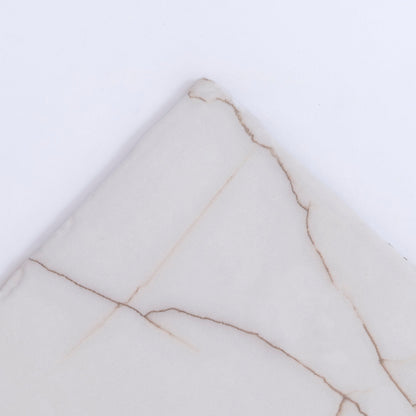 Close-up of Tosca’s Calacatta Soft sample, a light marble tile with subtle beige and brown veining on white.