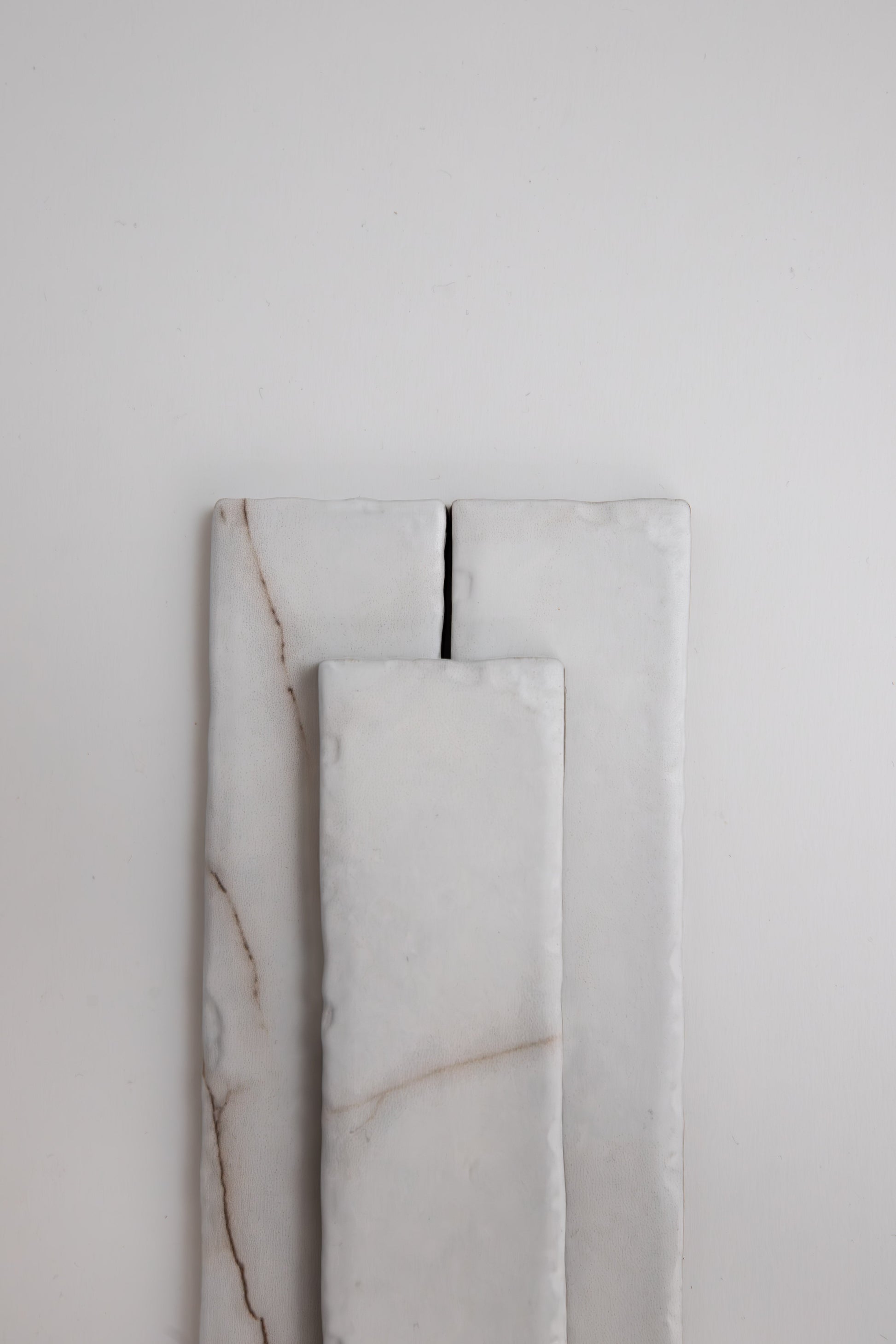 Three rectangular Calacatta Soft samples by Tosca, white with subtle brown lines, are stacked on a plain light background.