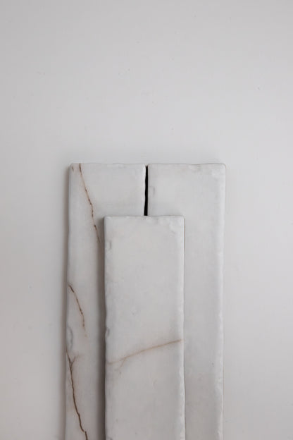 Three rectangular Calacatta Soft samples by Tosca, white with subtle brown lines, are stacked on a plain light background.