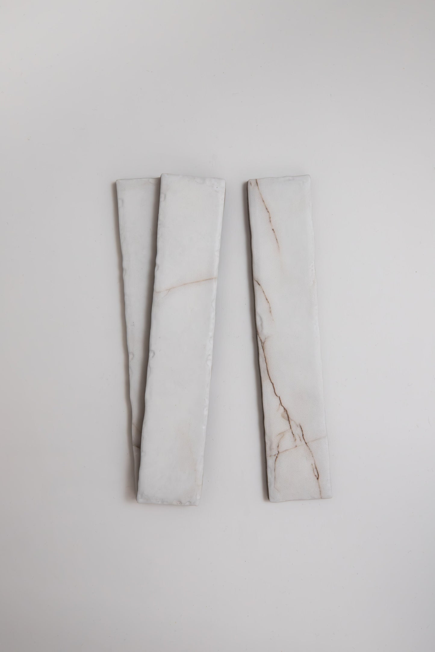 Two Calacatta Soft marble tile samples by Tosca, long and rectangular with faint brown veins on white.
