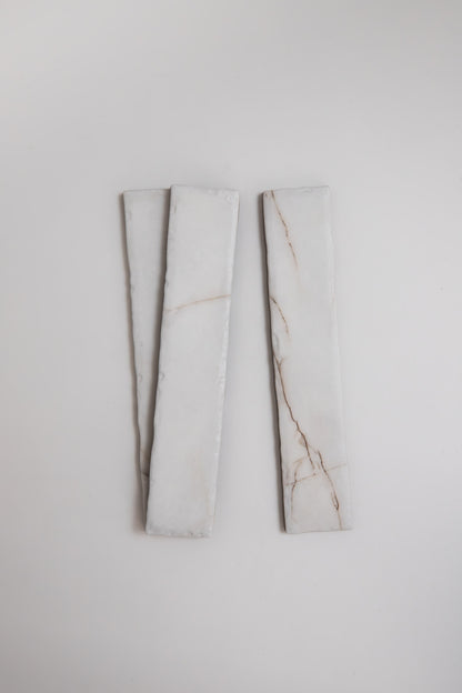 Two Calacatta Soft marble tile samples by Tosca, long and rectangular with faint brown veins on white.