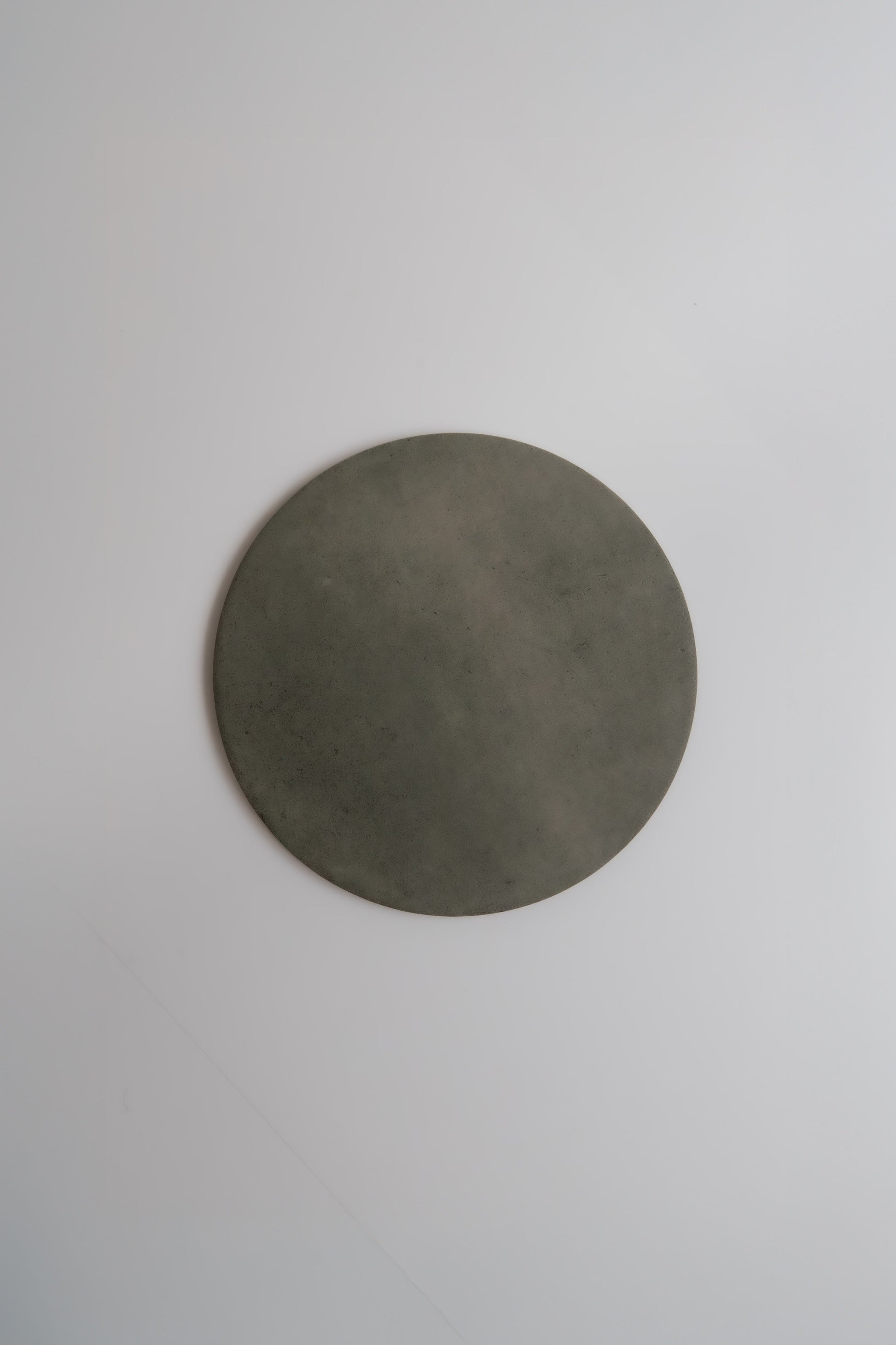 A round, flat, gray Cardon, Extra Sample by Finca shown on a plain white background.