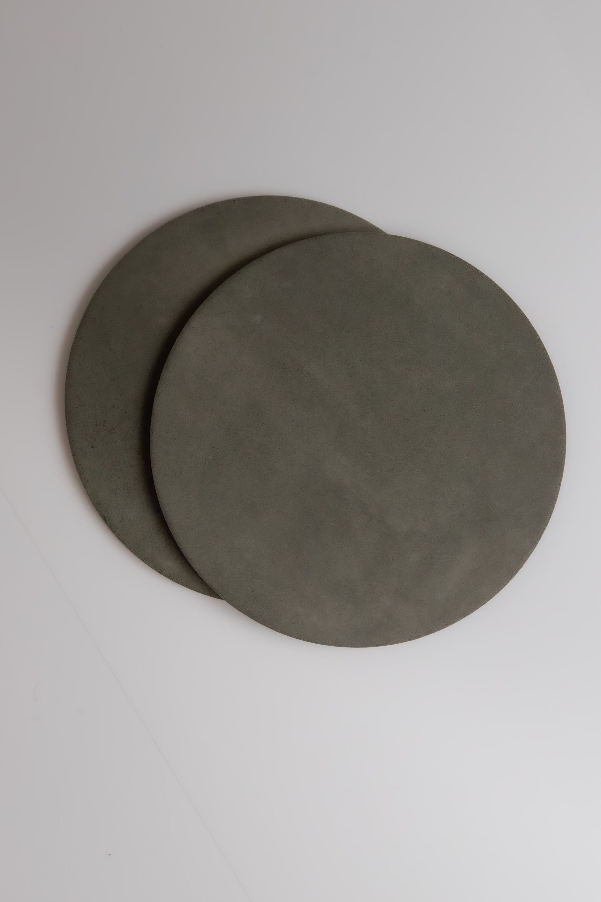 Two round, flat, gray Cardon Extra Sample plates by Finca overlap on a white surface.