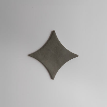 A gray, diamond-shaped Finca Cardon Extra Sample with curved edges on a plain, light background.