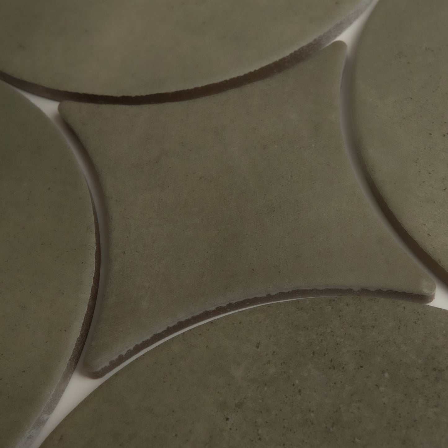 Close-up of Cardon, Extra Sample by Finca: greenish ceramic tiles with curved edges and white grout lines in a geometric pattern.