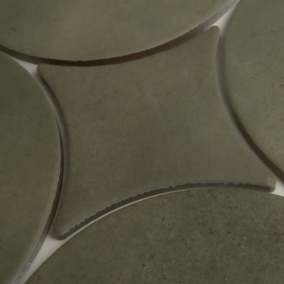 Close-up of Cardon, Extra Sample by Finca: greenish ceramic tiles with curved edges and white grout lines in a geometric pattern.