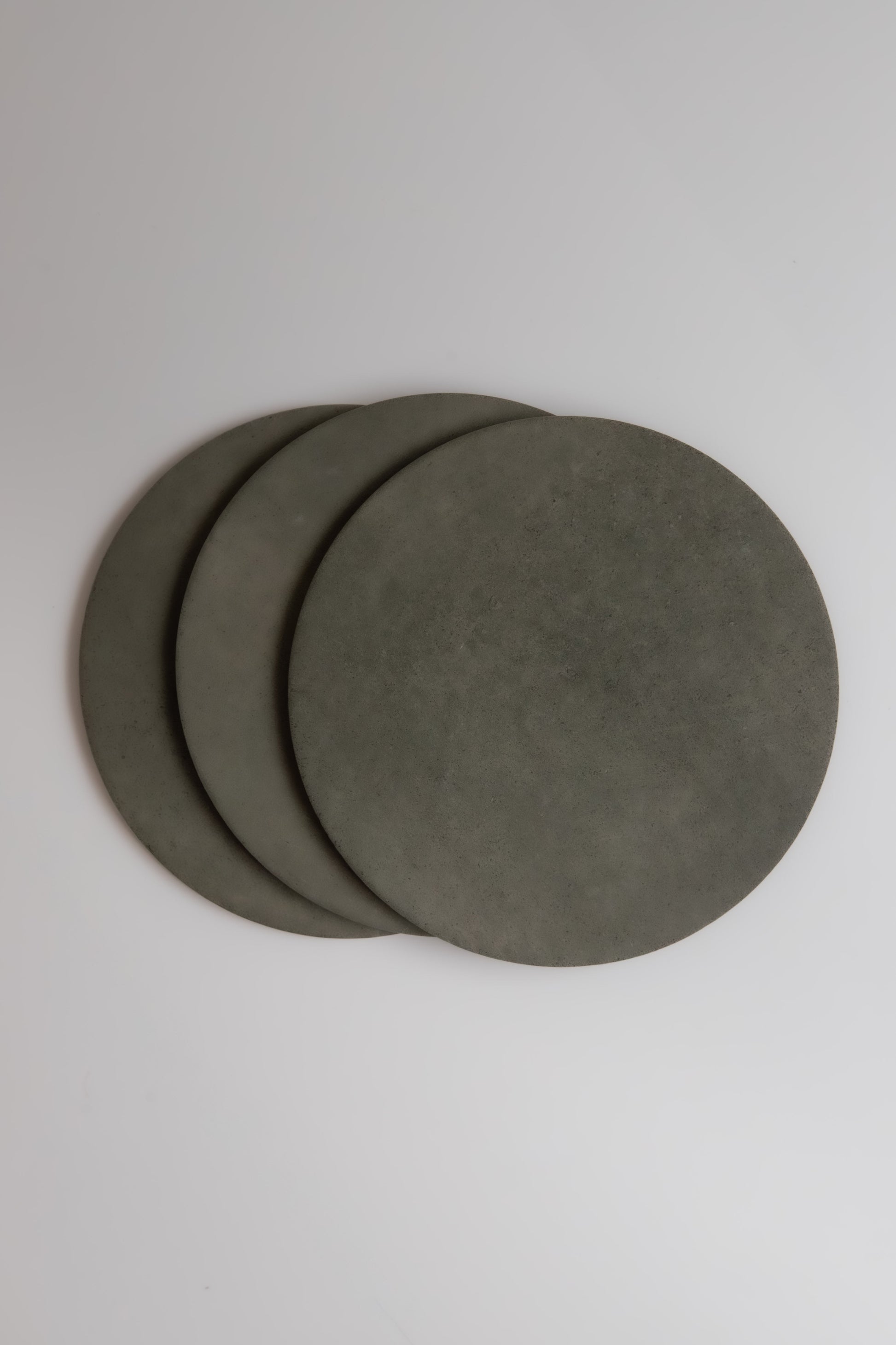 Four round Cardon stone coasters by Finca overlap on a plain white surface.