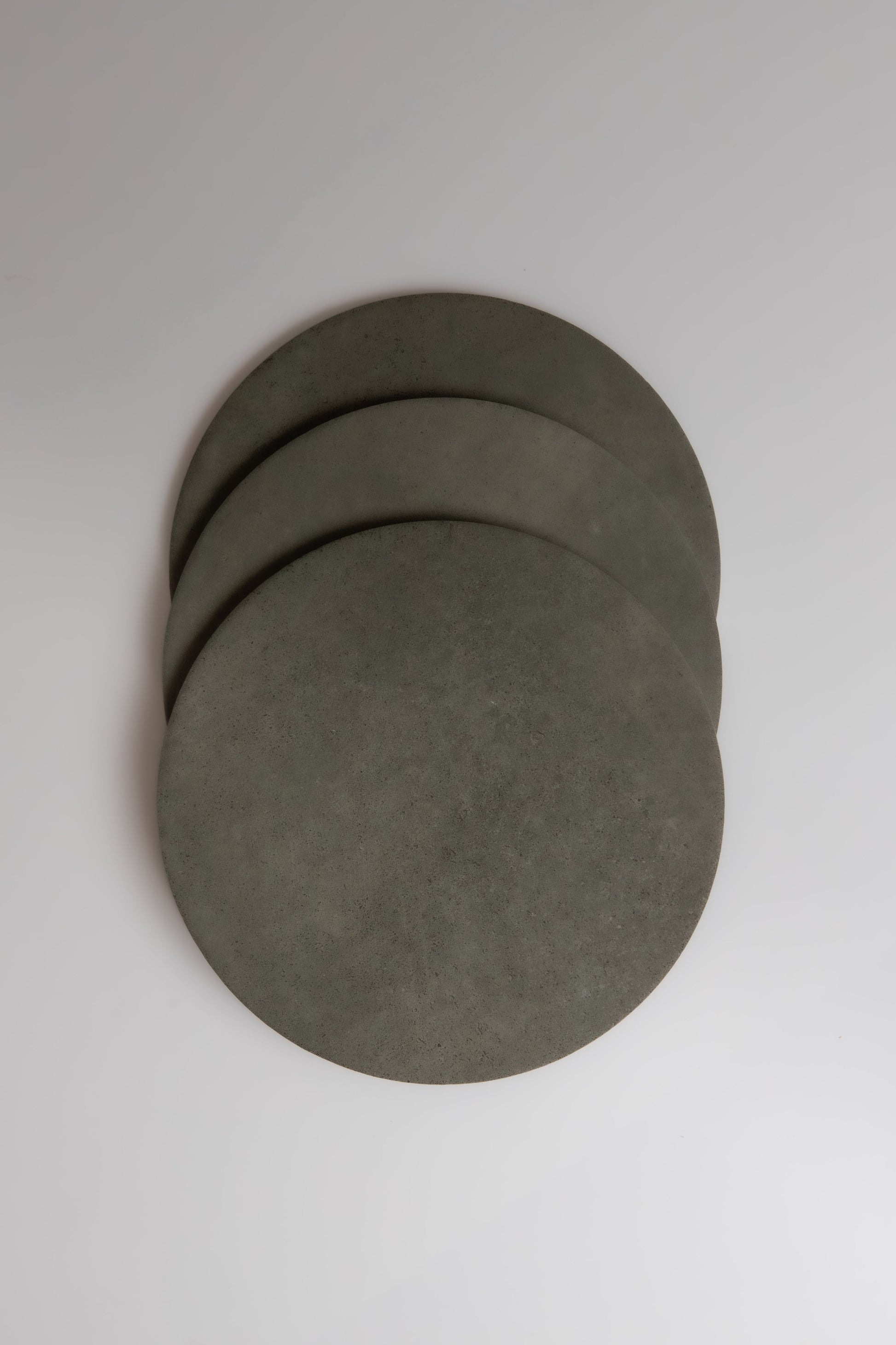 Three round, gray Finca Cardon coasters overlap on a white background.