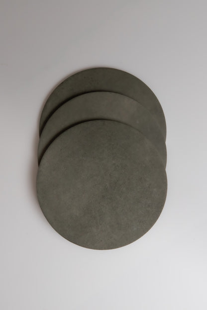 Three round, gray Finca Cardon coasters overlap on a white background.