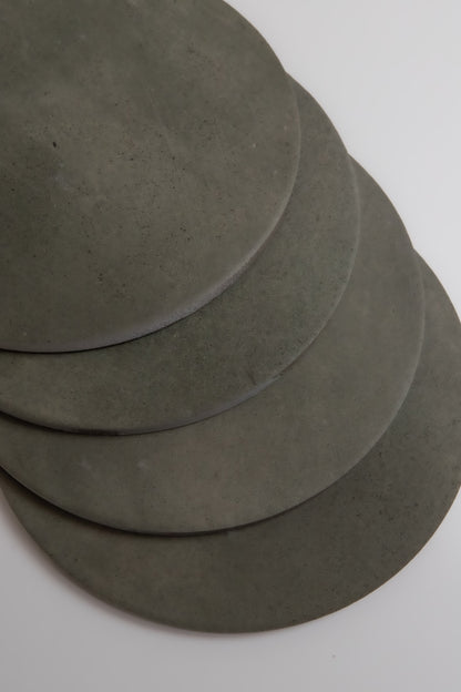 Four overlapping round gray Cardon stone slabs by Finca, arranged on a white surface.
