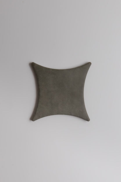 The Finca Cardon Sample is a square, gray, leather-like item with concave sides and rounded corners on a white background.