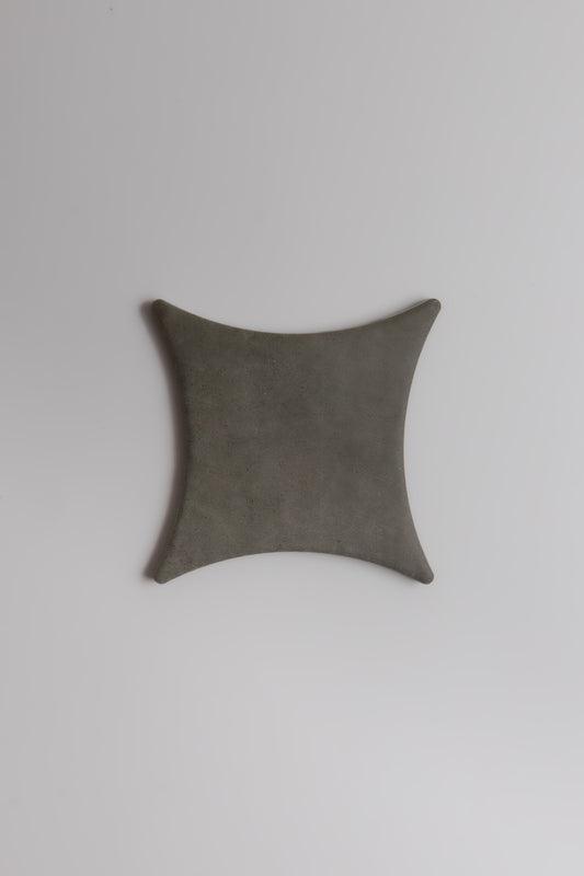 The Finca Cardon Sample is a square, gray, leather-like item with concave sides and rounded corners on a white background.