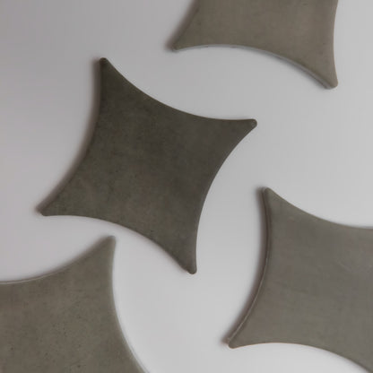 Cardon sample by Finca: gray, kite-shaped tiles on a white surface, some partially out of frame.