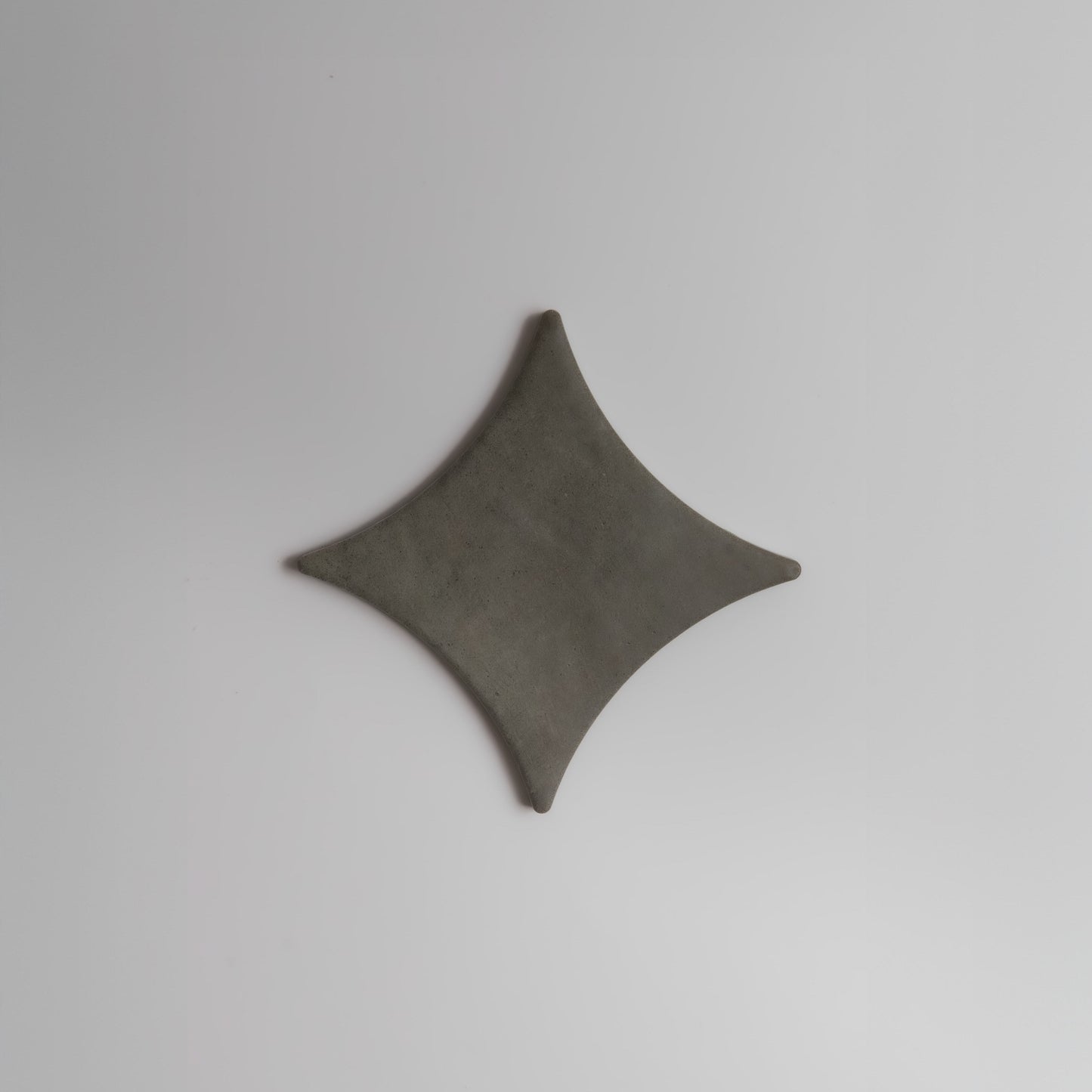 A gray, diamond-shaped Cardon Sample by Finca with curved edges, shown on a plain white background.