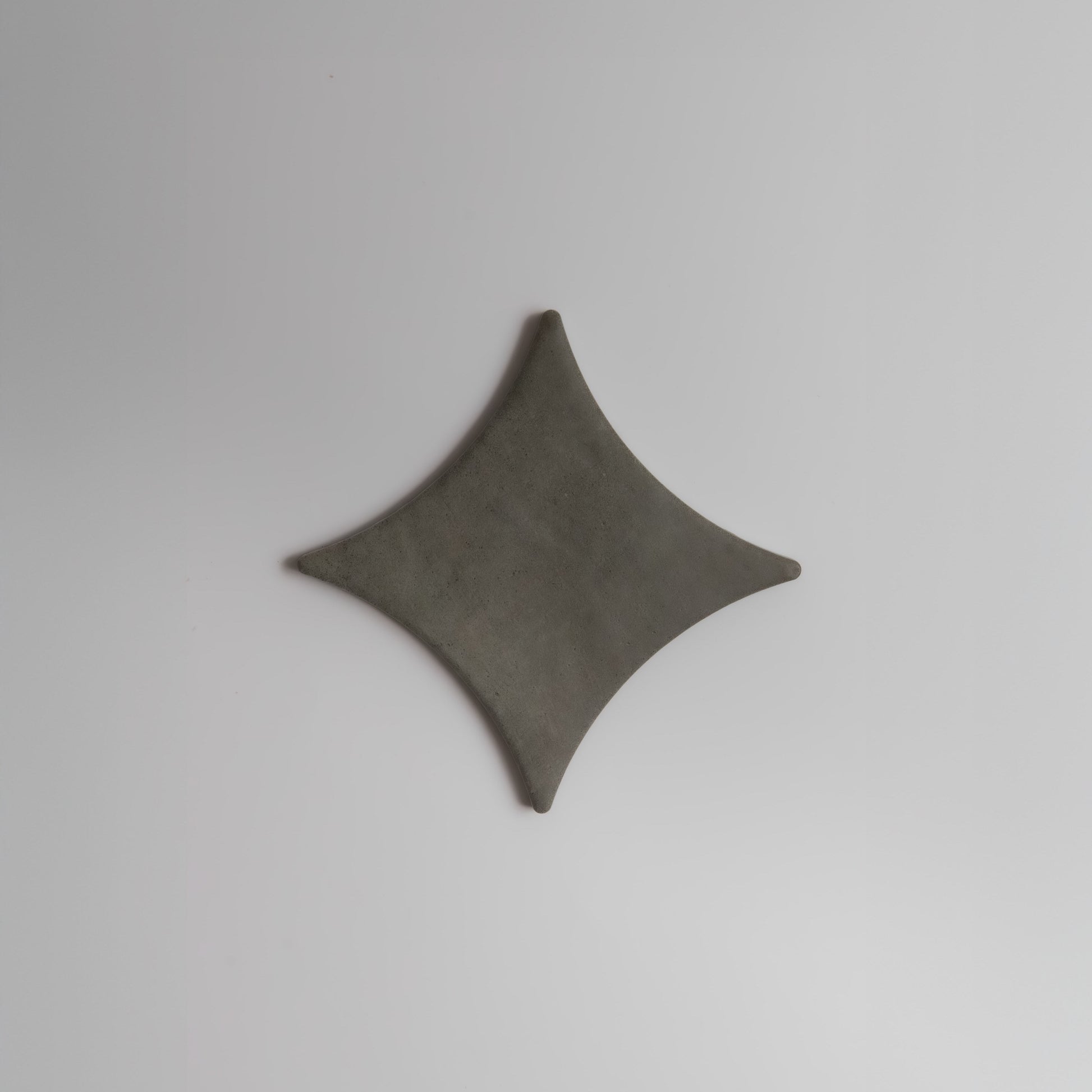 A gray, diamond-shaped Cardon Sample by Finca with curved edges, shown on a plain white background.