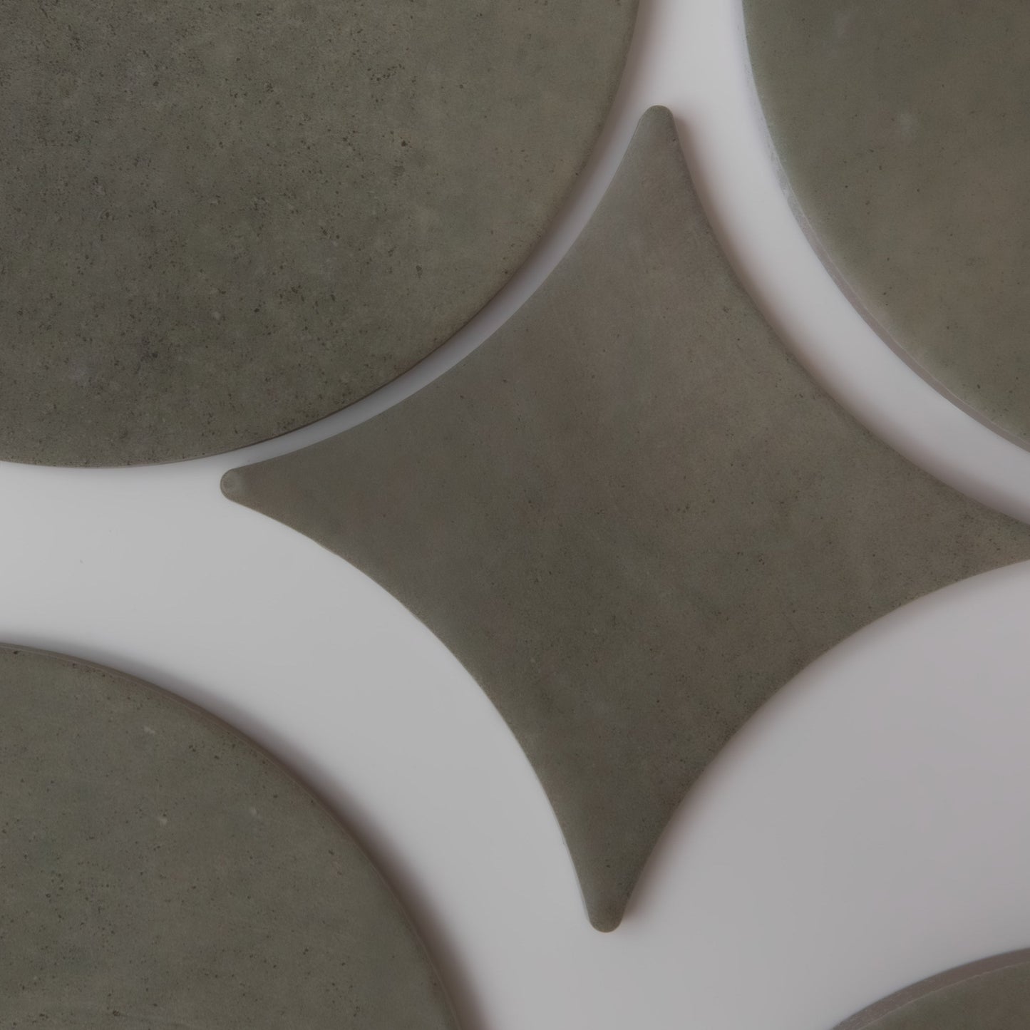 Finca Cardon Sample tiles in gray circles and diamonds create a geometric pattern on a white surface.