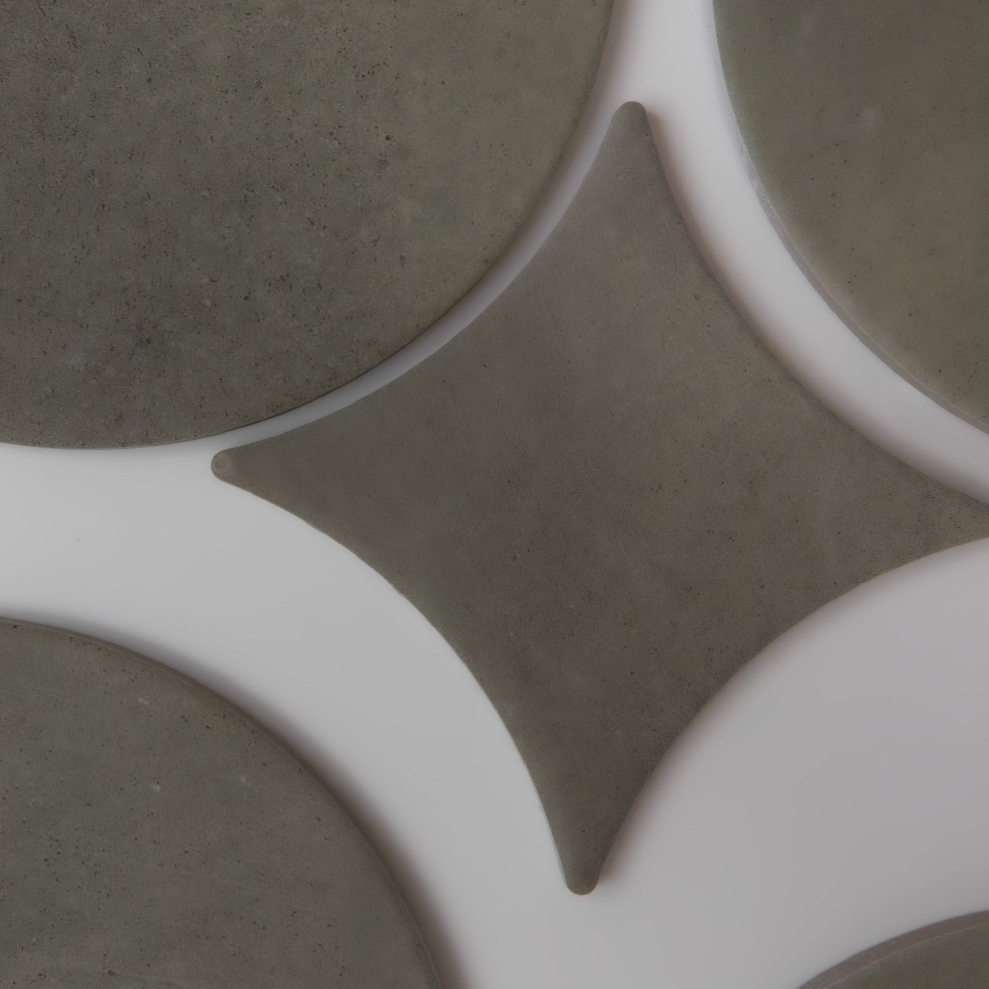 Finca Cardon Sample tiles in gray circles and diamonds create a geometric pattern on a white surface.