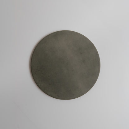 The Finca Cardon sample, a flat round gray stone, displayed on a plain white background.