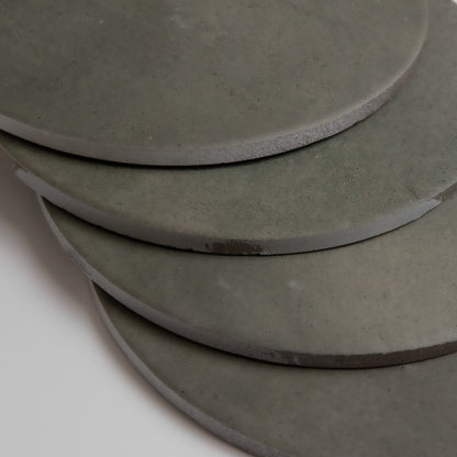 Four round gray Cardon tiles by Finca, sample size, stacked with slight overlap on a white background.