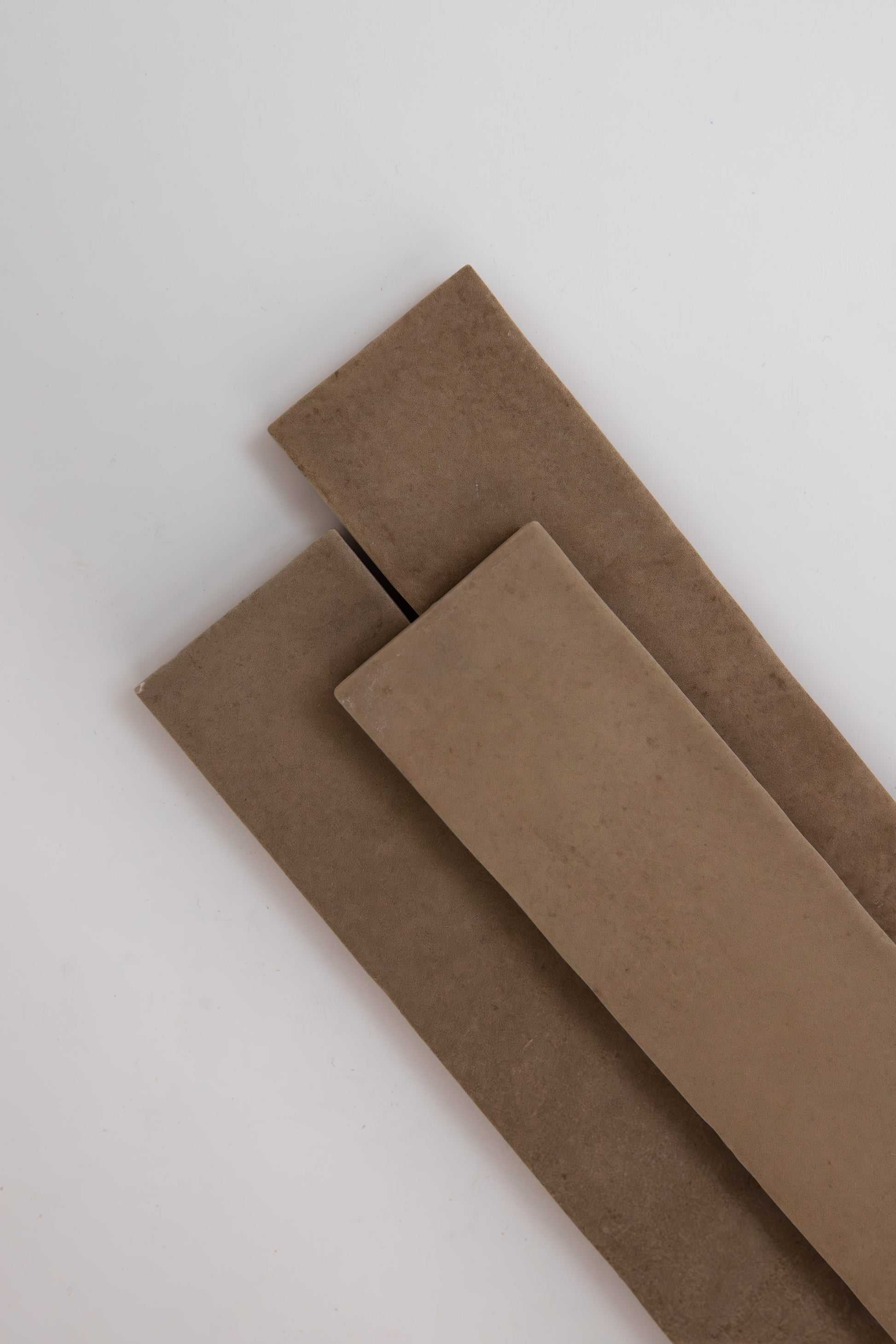 Two Castlegate Brown tiles by Cottage Ivy overlap on a white surface.