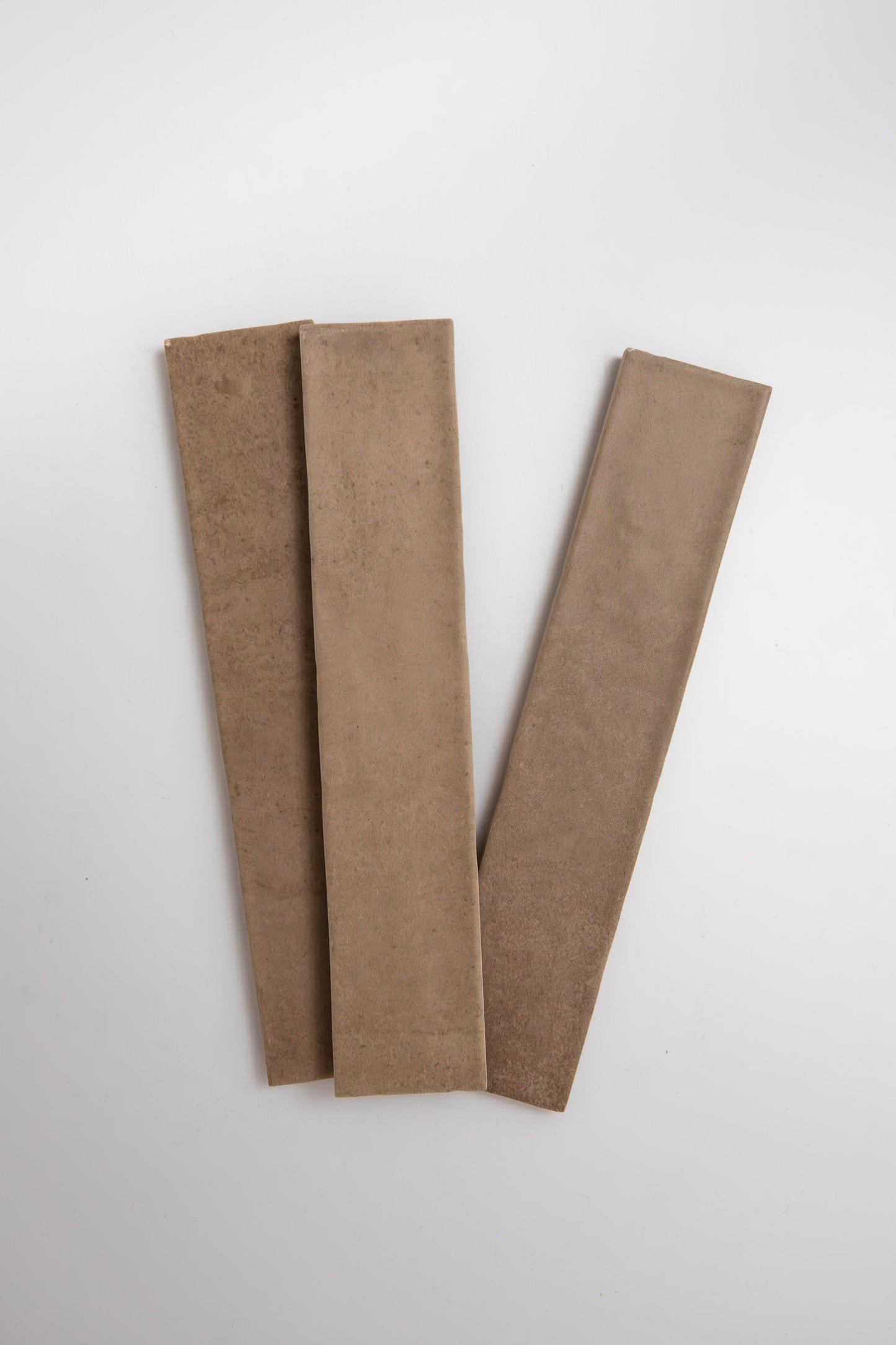 Three Castlegate Brown tiles by Cottage Ivy arranged in a fan shape on a white background.