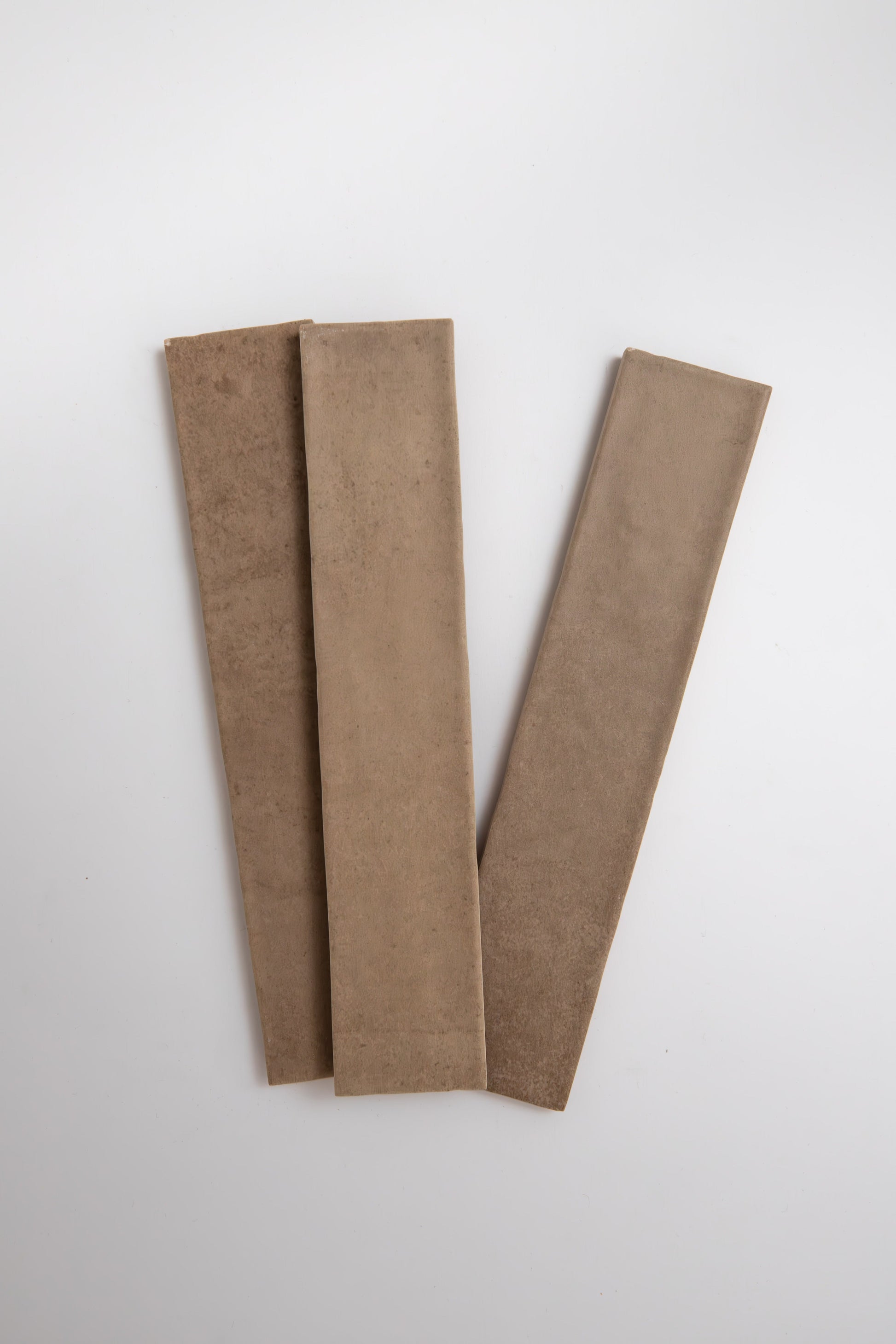Three Castlegate Brown tiles by Cottage Ivy arranged in a fan shape on a white background.