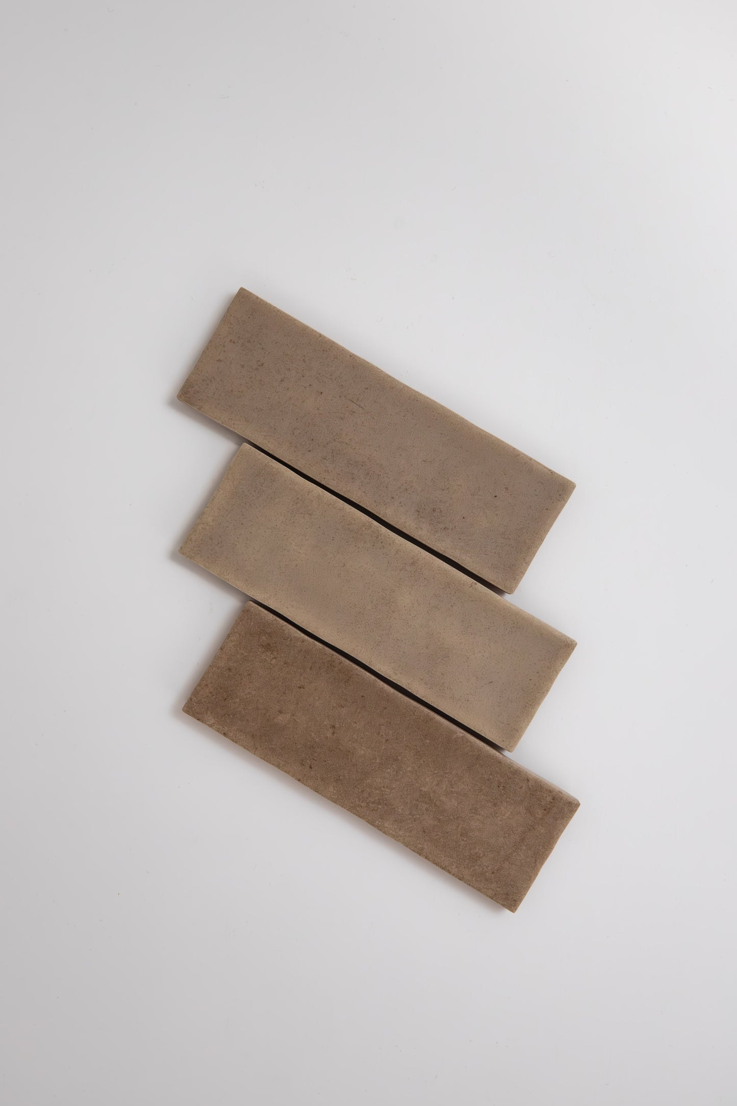 Three Castlegate Brown tiles by Cottage Ivy are arranged diagonally on a plain white background.