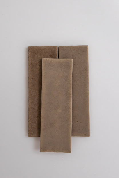 Three rectangular Castlegate Brown tiles by Cottage Ivy, light brown ceramic, overlap on a white background.