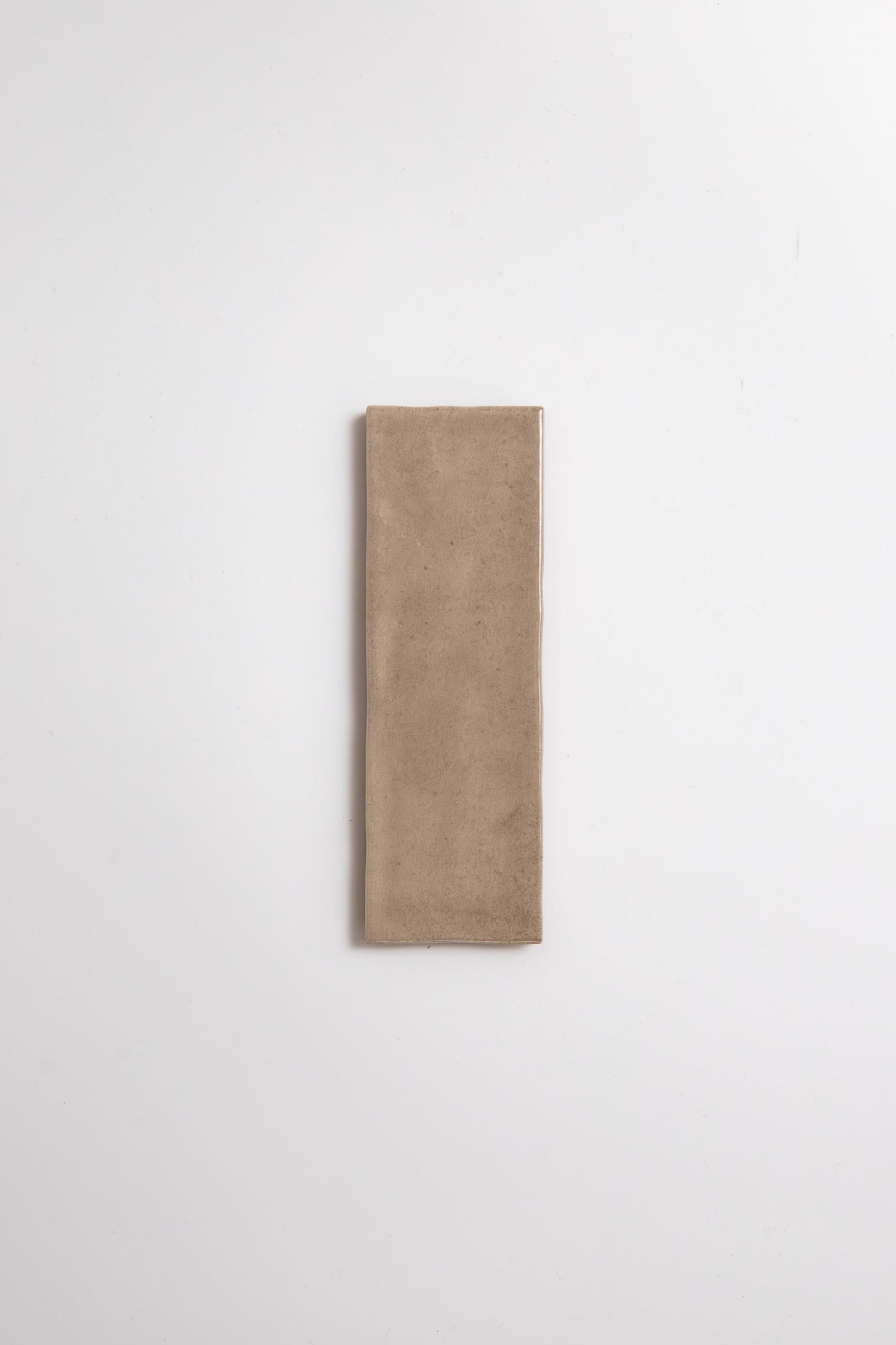 Castlegate Brown sample tile by Cottage Ivy, rectangular beige ceramic, centered on a plain white background.