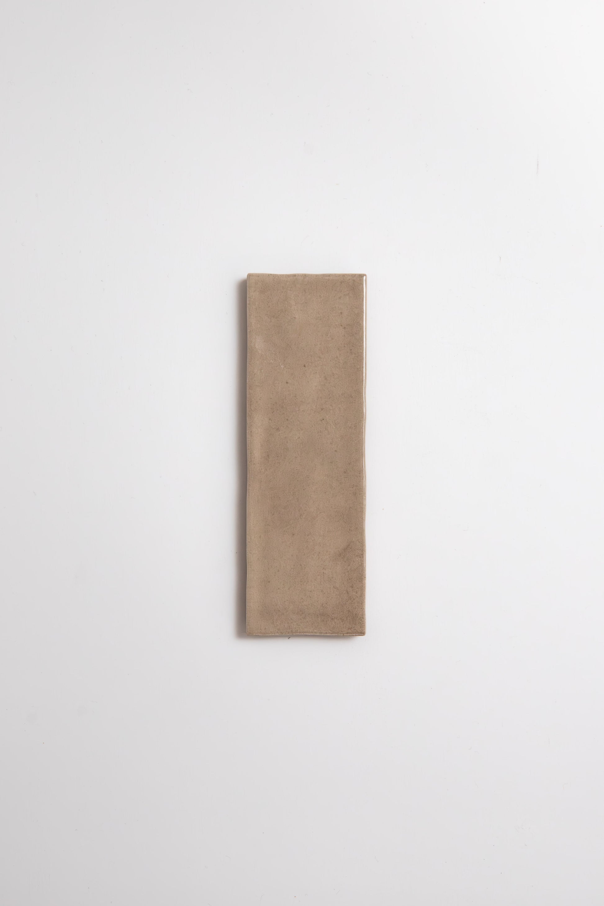 Castlegate Brown sample tile by Cottage Ivy, rectangular beige ceramic, centered on a plain white background.