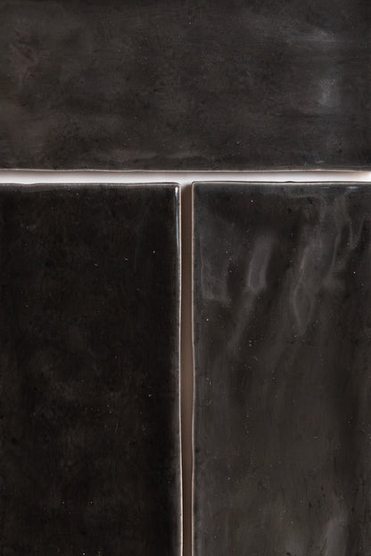 Close-up of three Cobbled Graphite tiles by Cottage Ivy, glossy black with grout lines in a T-shape.