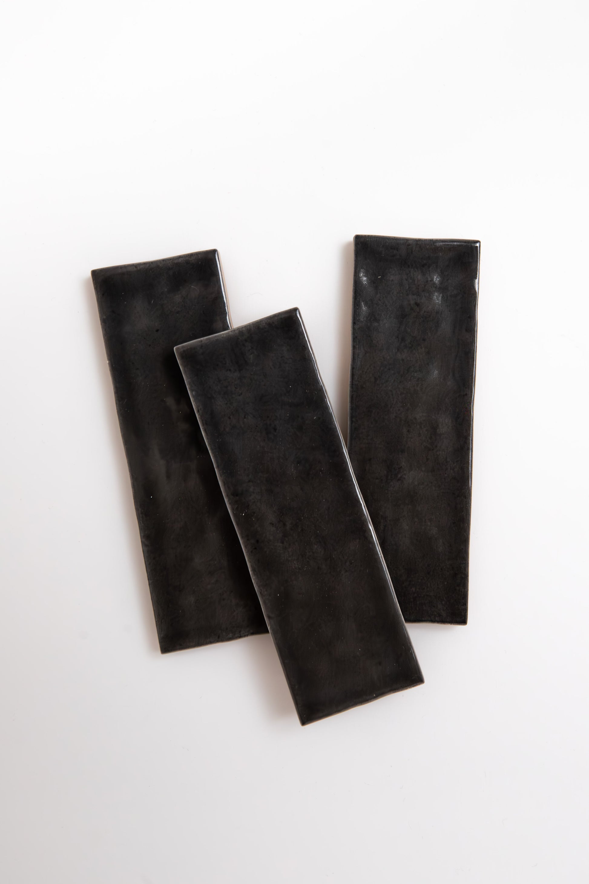 Three Cobbled Graphite plates by Cottage Ivy are arranged diagonally on a white background.