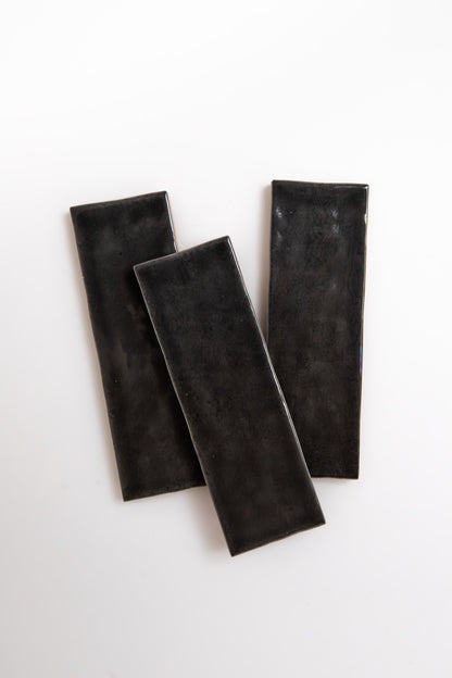 Three Cobbled Graphite plates by Cottage Ivy are arranged diagonally on a white background.