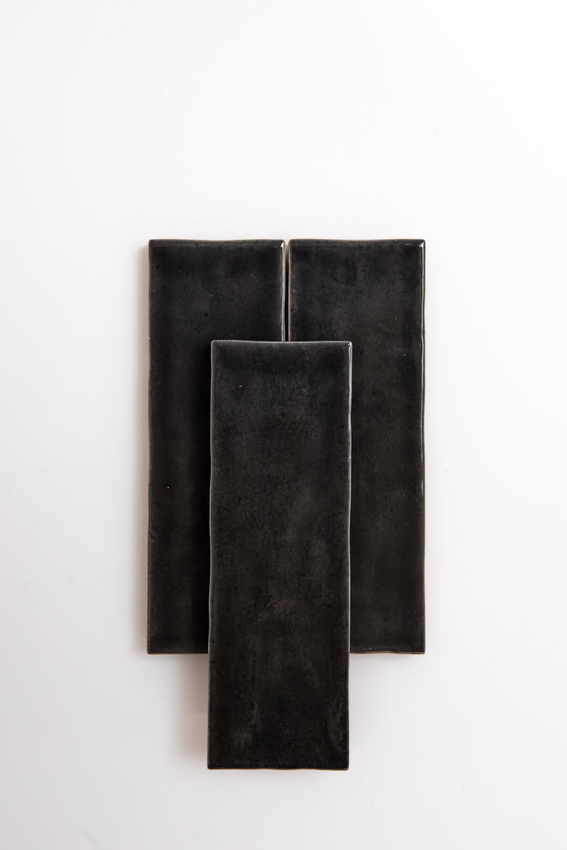 Three Cobbled Graphite tiles by Cottage Ivy overlap on a plain white background.