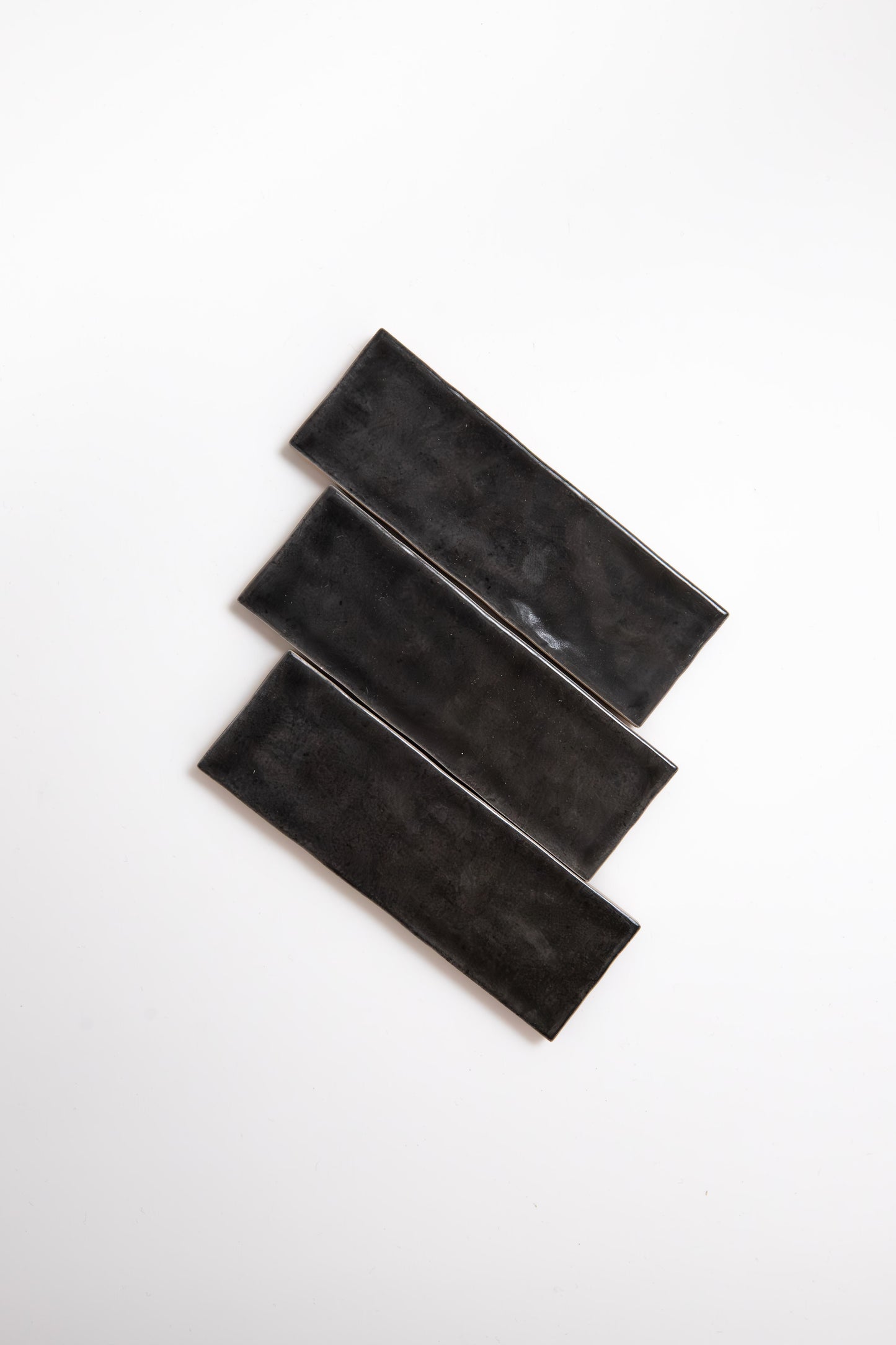Three Cobbled Graphite tiles by Cottage Ivy are arranged diagonally on a white background.