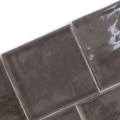 Close-up of four Cottage Ivy Cobbled Graphite glossy dark gray tiles arranged diagonally on a white background.