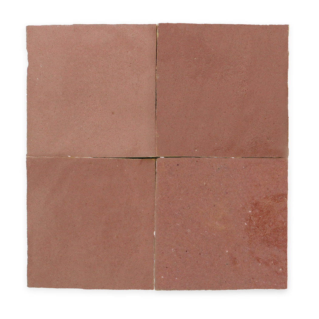 Four square, reddish-brown tiles arranged in a grid pattern, viewed from above against a white background.