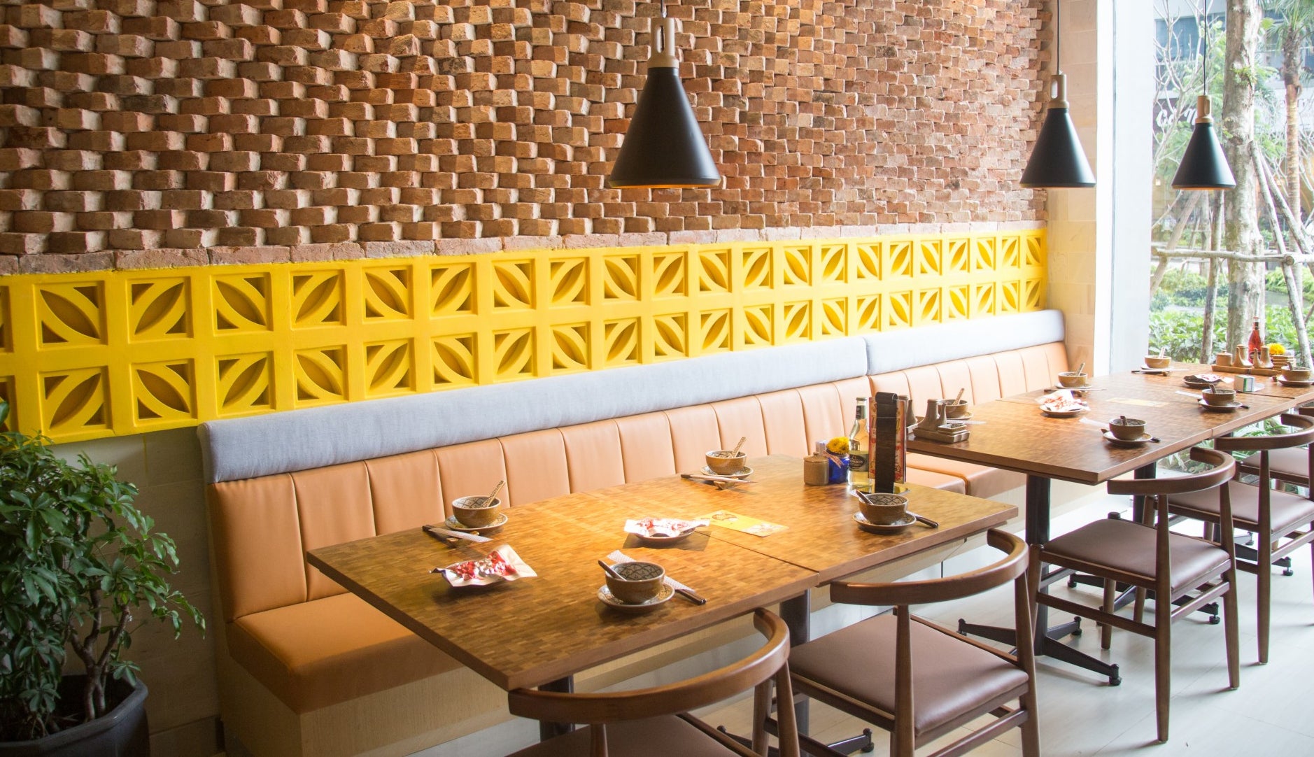 Modern restaurant featuring Coz tiles by New York Cement Tile, wooden tables, brown chairs, and yellow accent wall.